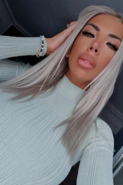 A very sexy blonde escort wearing a roll neck jumper 