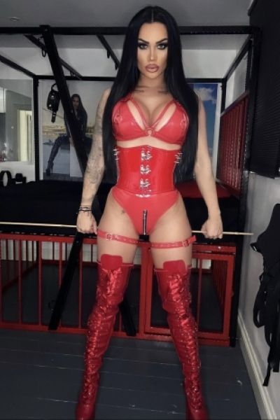 Mistress Nattasha Black standing in her dungeon holding a whip 